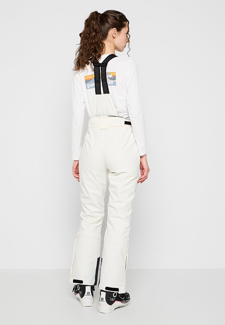 Witte sneeuwbroeken met verstelbare zwarte banden, ritszijden en een fitted ontwerp, gecombineerd met zwarte en roze skischrepen.