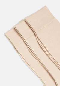 Calcetines de color rosa claro con textura suave y puños elásticos, apilados juntos mostrando una superficie lisa y uniforme con un brillo sutil.