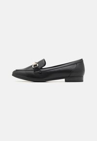 Mocassin en cuir noir avec un talon plat, présentant un accent métallique doré à l'avant et un design de bout lisse et arrondi.