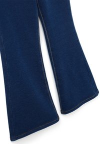 Jeans acampanados de color azul marino con una textura suave, que presentan costuras en contraste a lo largo de las costuras. El corte incluye una abertura lateral cerca del dobladillo.