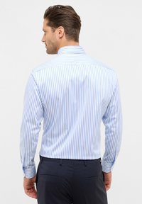 Camicia a righe a maniche lunghe in azzurro chiaro e bianco, con colletto classico e polsini con bottone, realizzata in tessuto morbido con un design aderente.