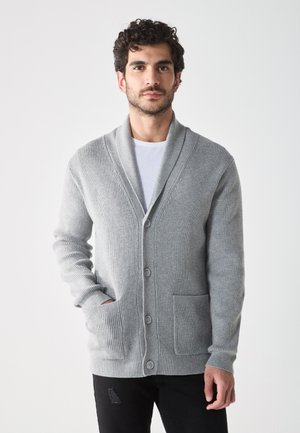 Cardigan grigio lavorato a maglia con colletto a scialle, bottoni frontali e tasche laterali. Presenta una texture a coste e un design slim fit.