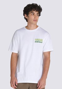 Camiseta blanca de algodón con el logotipo verde de "VANS" y el texto "custom classic" en el lado izquierdo del pecho. Cuello redondo, mangas cortas, corte relajado.
