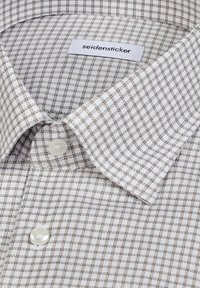 Chemise habillée à col avec un motif à carreaux blanc et brun, deux boutons blancs, et une étiquette de marque "seidensticker" à l'intérieur du col.