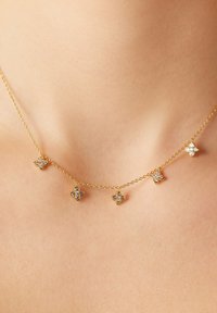 Gouden ketting met vijf bloemvormige pendanten, elk versierd met heldere stenen, waardoor een delicate en ingewikkelde uitstraling ontstaat.