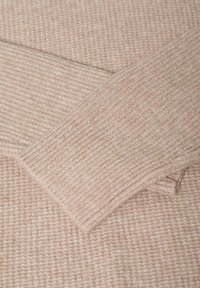 Beżowy sweter dziewiarski o ryflowanej fakturze i mankietach, wykonany z miękkiego i lekko puszystego materiału. Prosty design bez dodatkowych akcentów.