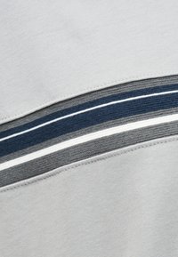 Ανοιχτό γκρι ύφασμα με οριζόντιες ριγωτές ρίγες σε σκούρο μπλε, γκρι, λευκό και ανοιχτό γκρι, περιτριγυρισμένο από ραμμένες ραφές.