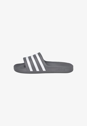 Chancla tipo slide gris de Adidas con tres franjas blancas en la correa y plantilla moldeada para mayor comodidad, mostrada de lado.