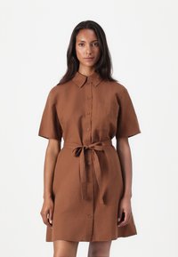 Brun kortermet kjole laget av stoff med krage, knapper foran og belte i midjen; har en brystlomme.
