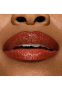 Close-up of lips with a smooth, glossy finish in deep reddish-brown color; well-defined shape with a natural pink undertone and visible teeth.