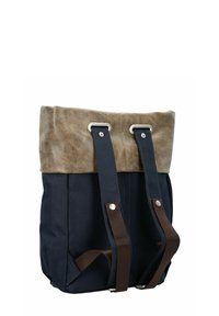 Zaino in tela con parte superiore in pelle marrone, corpo blu navy, due spallacci in tessuto marrone, dettagli in metallo argentato e design con parte superiore piegata.