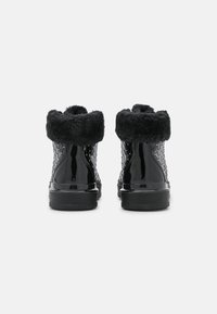 Černé lakované kotníkové boty s měkkým kožešinovým manžetou, texturované boky s mřížkovaným vzorem a plochou gumovou podrážkou.