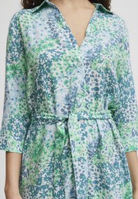 Rochie cu nasturi înflorată în nuanțe de albastru și verde, având talie legată, mâneci trei sferturi și un material ușor cu modele variate.