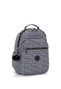 Ryggsäck i mönstrad svart och vit tyg, med dubbla dragkedjor, en framficka och en fluffig charm fäst på sidan.