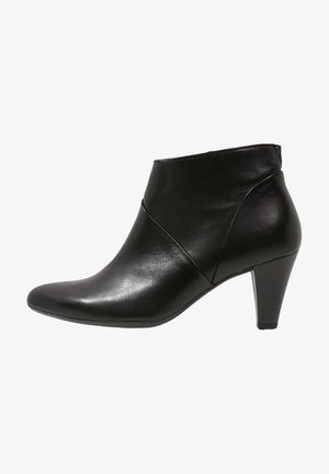 Bottes courtes en cuir noir avec un bout pointu, des détails de ligne asymétrique et un talon modéré. Texture lisse et design épuré.