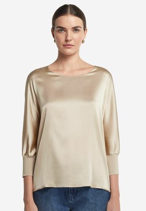 Satinblus i ljus beige med båthals, trekvartslånga puffärmar och en lös passform, i kombination med denim. Slät textur och subtil lyster.