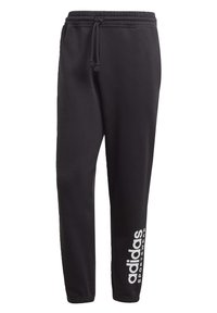 Pantaloni della tuta neri realizzati in tessuto morbido, dotati di un cinturino elastico con cordino e stampa del logo bianco adidas sulla parte inferiore della gamba.