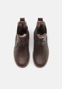 Botas de tobillo de cuero marrón con un acabado suave, que cuentan con un forro interior suave, punta redondeada y paneles laterales elásticos para facilitar el uso.