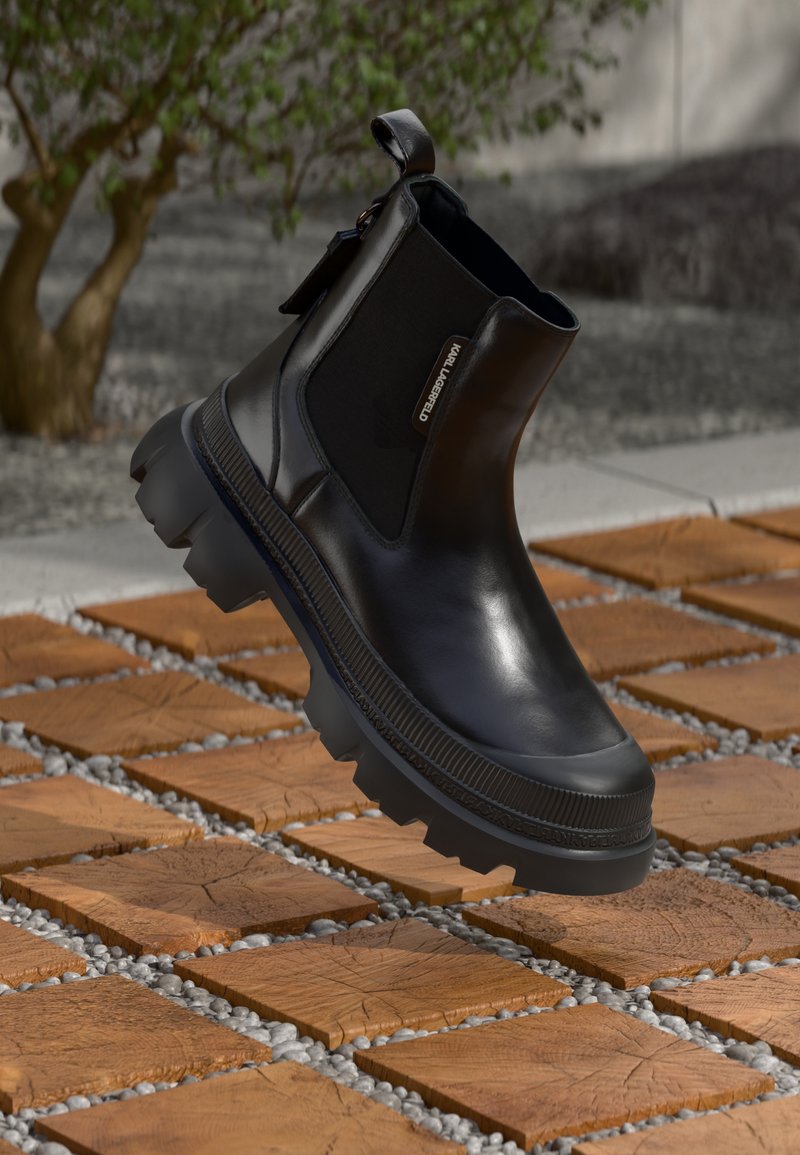 Černé kožené kotníkové boty s robustní gumovou podrážkou, elastickými bočními panely a poutkem. Detailně provedené s logem na straně.