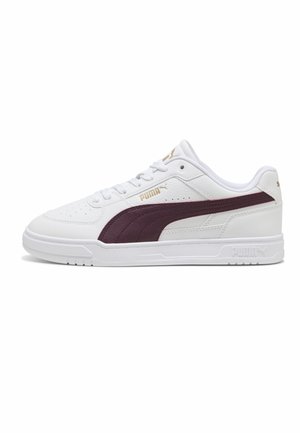 Baskets Puma blanches à tige basse avec une bande latérale bordeaux, des accents dorés du logo, un bout perforé et une semelle en caoutchouc blanche sur un fond uni.