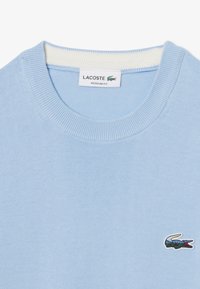 Lichtblauwe katoenen crewneck trui met een geribde kraag en een klein geborduurd Lacoste-logo op de linkerkant van de borst. Regelmatige pasvorm.