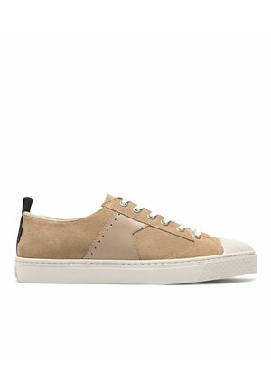 Baskets en suède beige avec des accents en cuir lisse, semelle en caoutchouc blanc et fermeture à lacets grise. Présente un tirant noir à l'arrière.