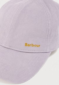 Καπέλο από βελούδο κορντόρι σε μωβ απόχρωση με καμπυλωτό γείσο, που φέρει κεντημένο με χρυσή κλωστή το λογότυπο "Barbour" στο μπροστινό μέρος. Διακρίνεται η χαρακτηριστική ραβδωτή υφή σε όλη την επιφάνεια.