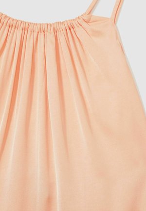 Halenka bez rukávov v broskyňovej farbe so zozbieraným výstrihom a jemnou, hladkou textúrou; látka sa jemne splýva, čo vytvára plynulý siluet.