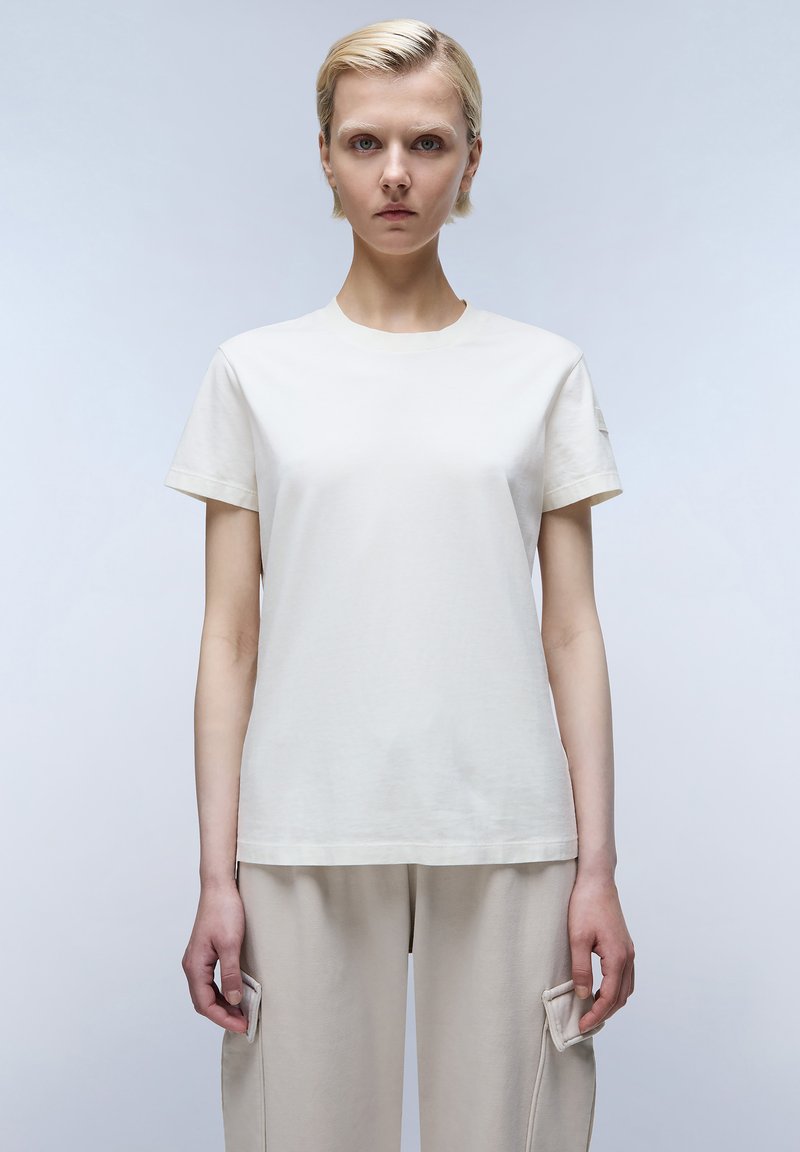Lichtbeige katoenen t-shirt met korte mouwen en een ronde hals. Gave textuur, eenvoudig ontwerp en een relaxte pasvorm.