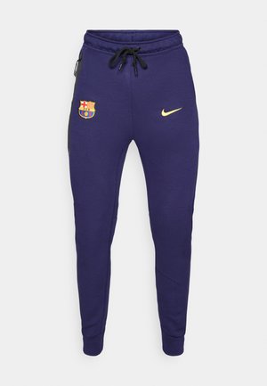 Pantalons de survêtement bleu marine avec un logo Nike doré, un emblème brodé du FC Barcelone et des accents noirs sur les côtés, avec une taille à cordon.