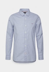 Camisa de manga larga con botones, con un patrón a cuadros azul y blanco, cuello con solapa y un pequeño logotipo en el pecho.