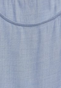 Ljusblått tyg med en slät, lätt strukturerad yta. Har en rundad halsringning och en enkel, klassisk design.