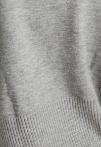 Szary sweter wykonany na drutach, charakteryzujący się gładką teksturą i żebrowanym wykończeniem. Materiał wydaje się miękki i lekki, z klasycznym okrągłym dekoltem.