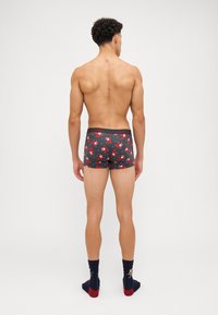Männer Boxershorts in Dunkelgrau mit einem roten und weißen Karikatur-Weihnachtsmann-Muster. Mit einem Markenbund und passenden Socken mit festlichem Design.