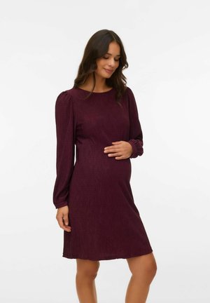 Graviditetskjole i dyb bordeaux, ribbet tekstur, over-knee længde, med lange ærmer og rund halsudskæring, designet til komfort og pasform.