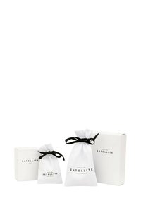 Dos bolsitas de tela blanca con cordones negros y dos cajas blancas, todas etiquetadas como "Satellite Paris-Francia" en texto negro.