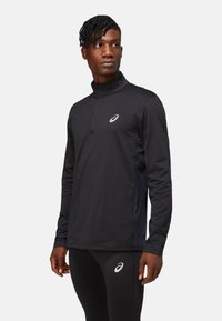 Black long-sleeve quarter-zip athletic top with a high collar, featuring a reflective logo and contrasting side panels for enhanced mobility.