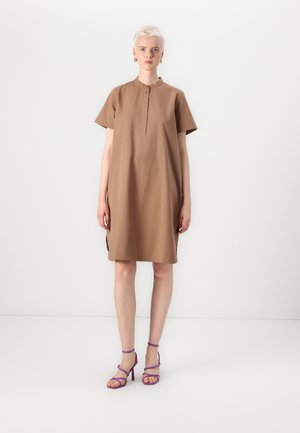 Abito marrone a maniche corte con colletto rotondo e patta con bottoni, caratterizzato da spacchi laterali. Abbinato a sandali con tacco alto a strappy viola.