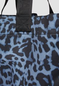 Niebieska i czarna torba tote w leopardzim wzorze, wykonana z wytrzymałego materiału, z kontrastującymi teksturowanymi paskami oraz prostym, funkcjonalnym designem.