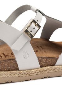Sandalo in pelle bianca con una soletta in sughero, caratterizzato da un accento in oro sulla fascia e una texture della suola avvolta in juta.