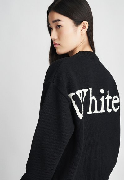 Pull en tricot noir avec le mot "White" en grand sur le dos. Le design comprend un col côtelé et un tissu texturé.