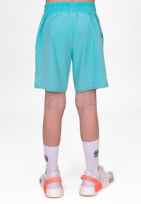 Un par de pantalones cortos deportivos de color azul aqua, hechos de tela ligera, con una cinturilla elástica y bolsillos laterales. Llevados con calcetines blancos y zapatillas.