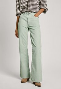 Mint green wide-leg jeans with a high waist and front pockets, paired with a checkered button-up shirt. Subtle texture visible.