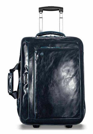 Maleta de cuero negra con mango retráctil, bolsillo frontal con acentos de cremallera azul y una textura suave. Se sostiene sobre cuatro ruedas pequeñas.
