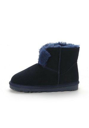 Botte à cheville en suede bleu marine avec une doublure et une bordure en fausse fourrure douce et pelucheuse. Dotée d'un bout rond et d'une semelle en caoutchouc plate pour la stabilité.