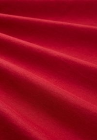 Katoenen stof in rijk rood met een soepele textuur; heeft subtiele plooien en golven die het gewicht en de val laten zien.