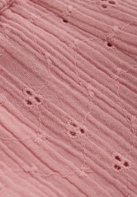 Helles rosa strukturiertes Gewebe mit einem gerippten Muster und kleinen blumigen Stickdetails, die ein zartes und subtil gestaltetes Design schaffen.
