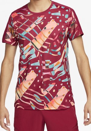 Bordowa koszula z krótkim rękawem z kolorowymi abstrakcyjnymi wzorami geometrycznymi i nutami muzycznymi, noszona przez osobę w dopasowanych bordowych szortach.