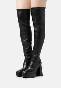 Black leather thigh-high boots with a block heel, featuring a zipper detail on the side and smooth texture, designed for a fitted look.