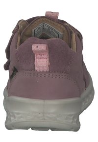 Różowe zamszowe sneakersy z wyściełanym tyłem, elastycznymi paskami i teksturowaną białą podeszwą. Wnętrze ma beżowe wykończenie i metkę.